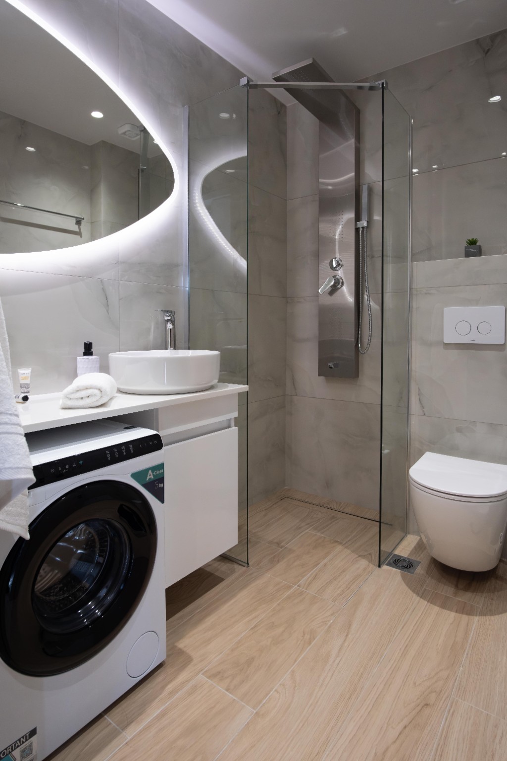 Modern marble-effect bathroom with walk-in rainfall shower and washing machine